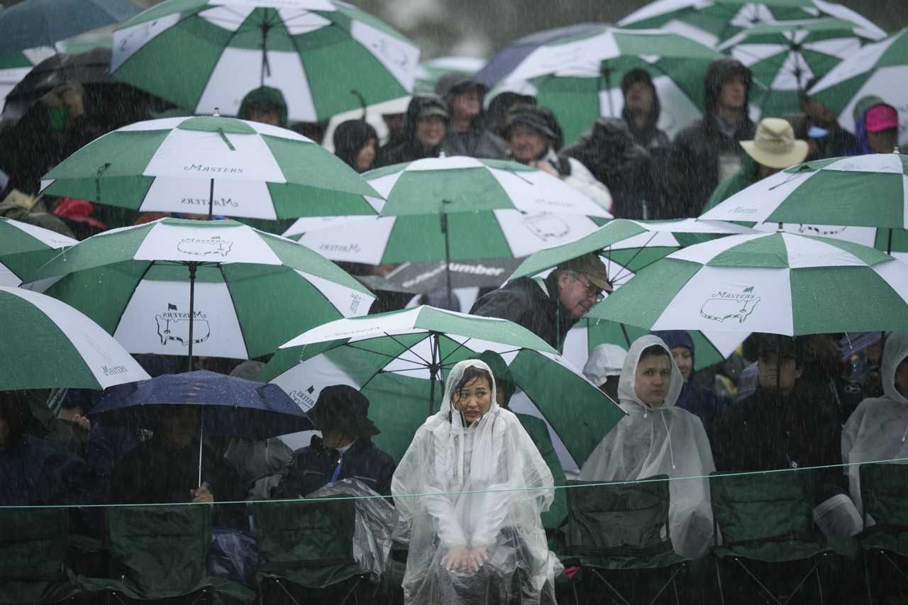 Patrons watch in the rain on the 18th hole during the weather delayed second round of the Masters golf tournament at Augusta National Golf Club on Saturday, April 8, 2023, in Augusta, Ga. (AP Photo/Matt Slocum)