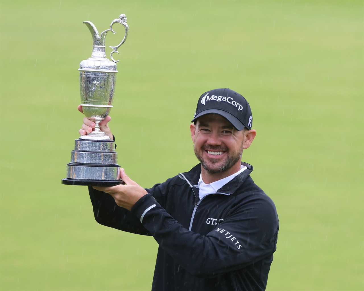 a man wearing a megacorp hat holds a trophy