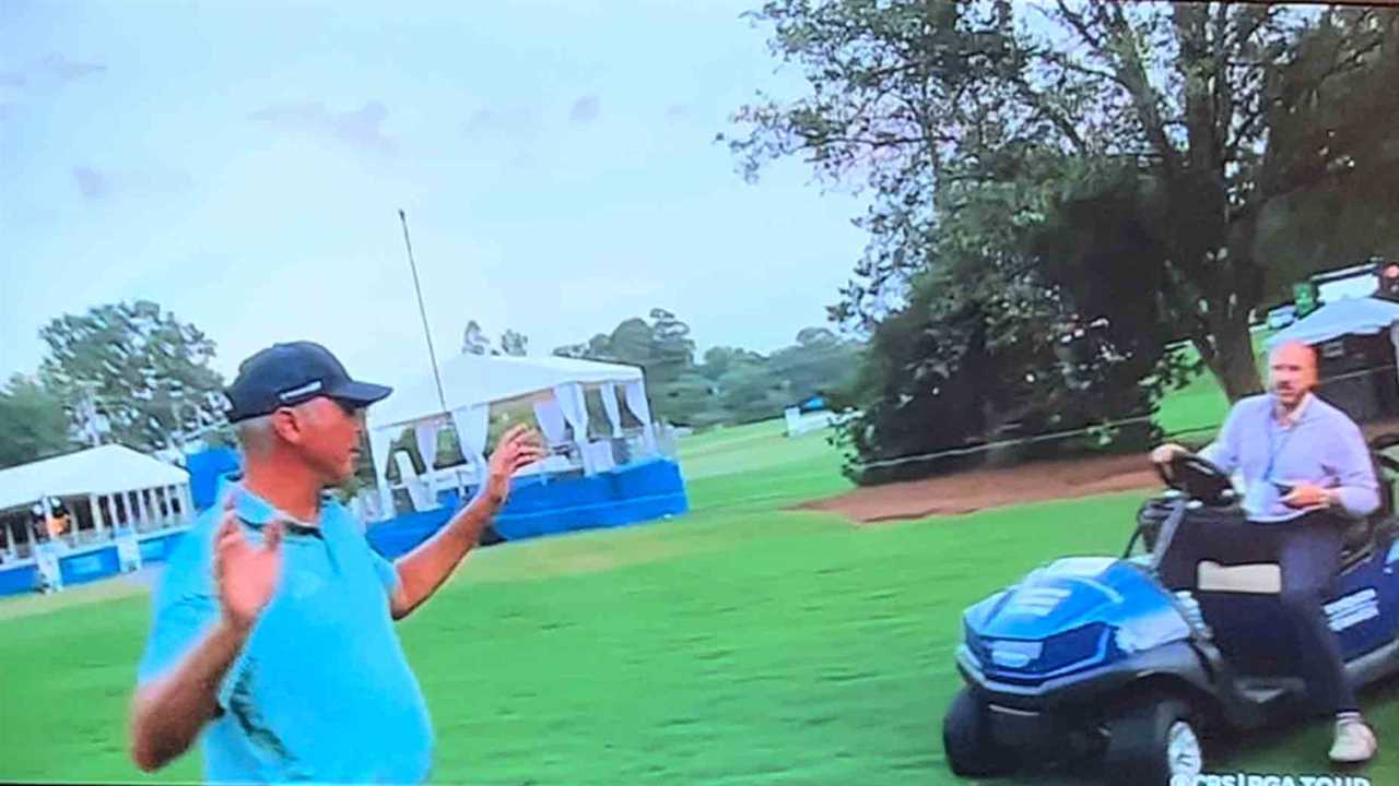 a man on a golf course talking to another man on a golf cart