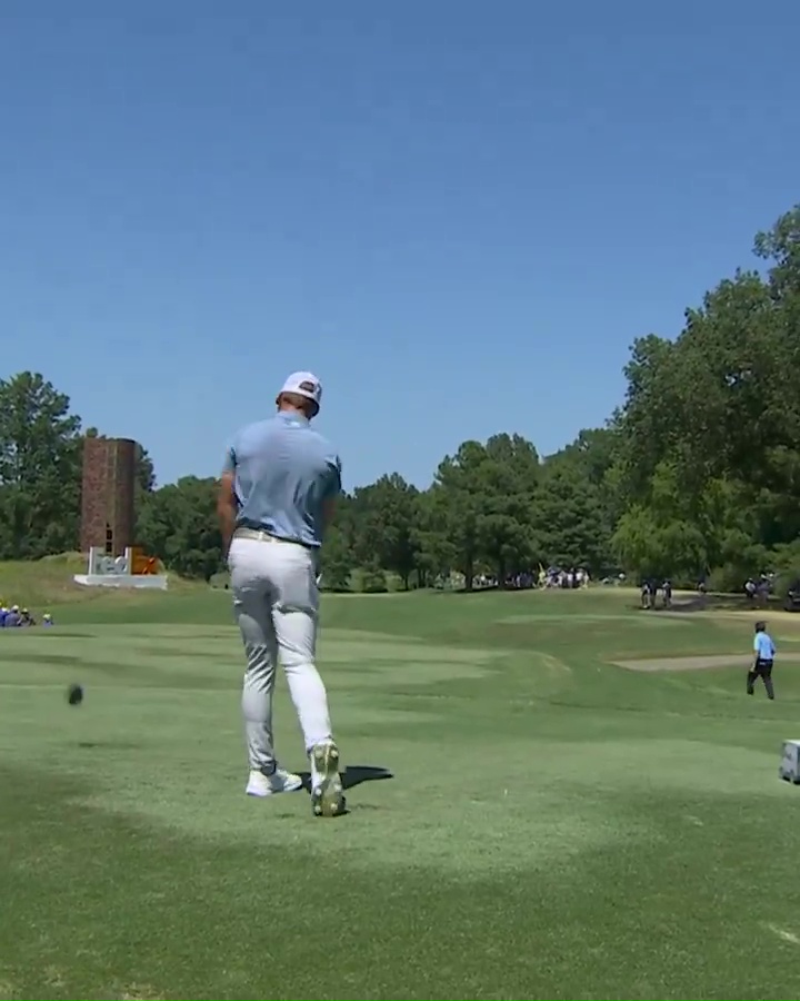 a man in a blue shirt and white pants is playing golf