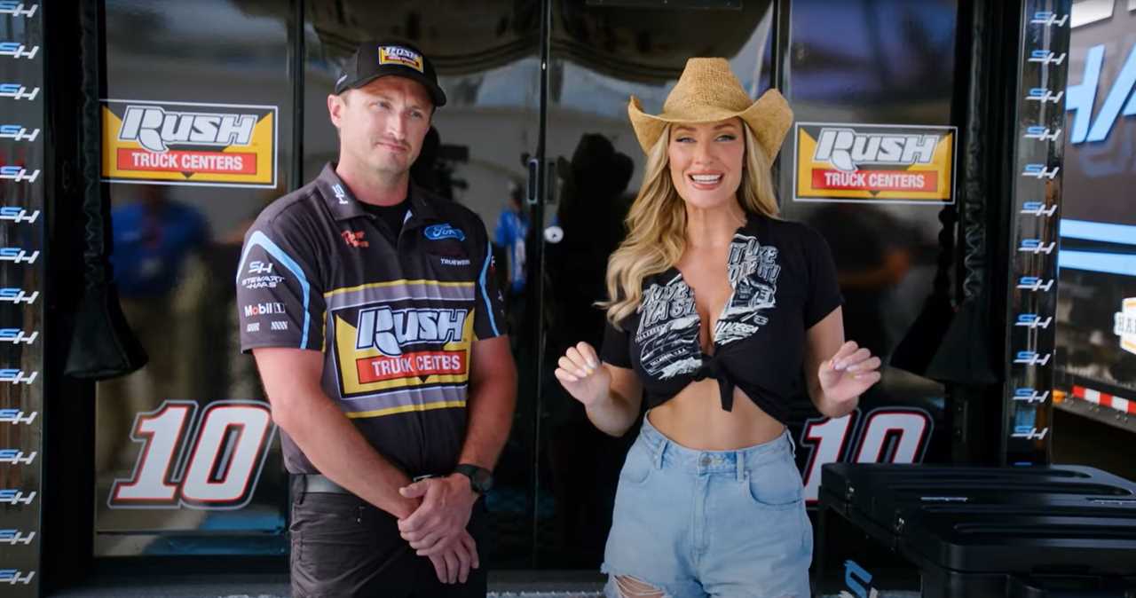 a man in a rush truck centers shirt stands next to a woman in a cowboy hat