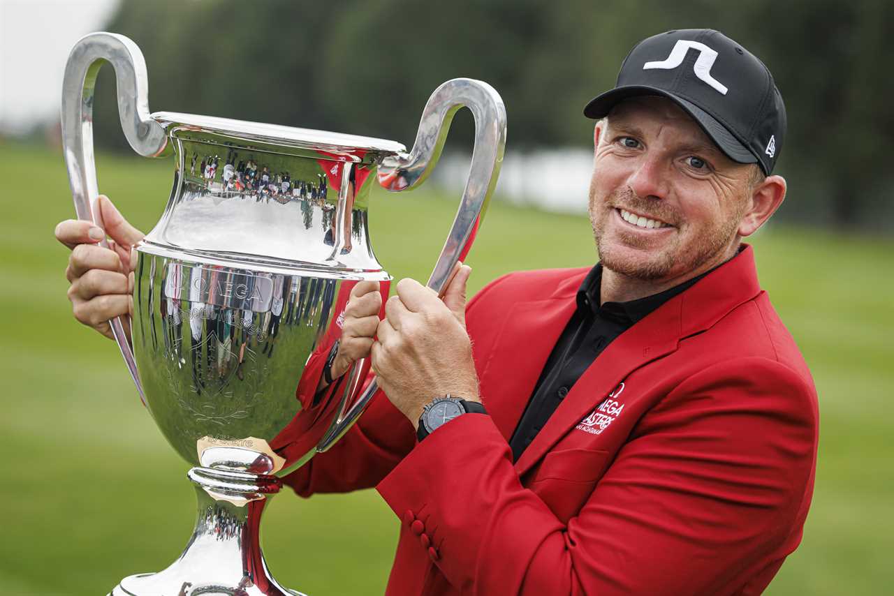 a man in a red jacket is holding a trophy