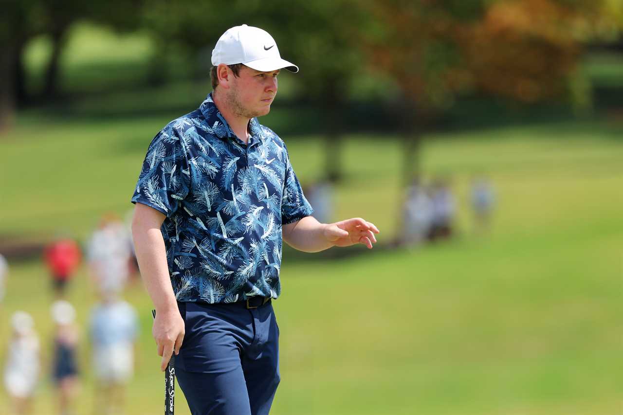 a man wearing a nike hat is walking on a golf course