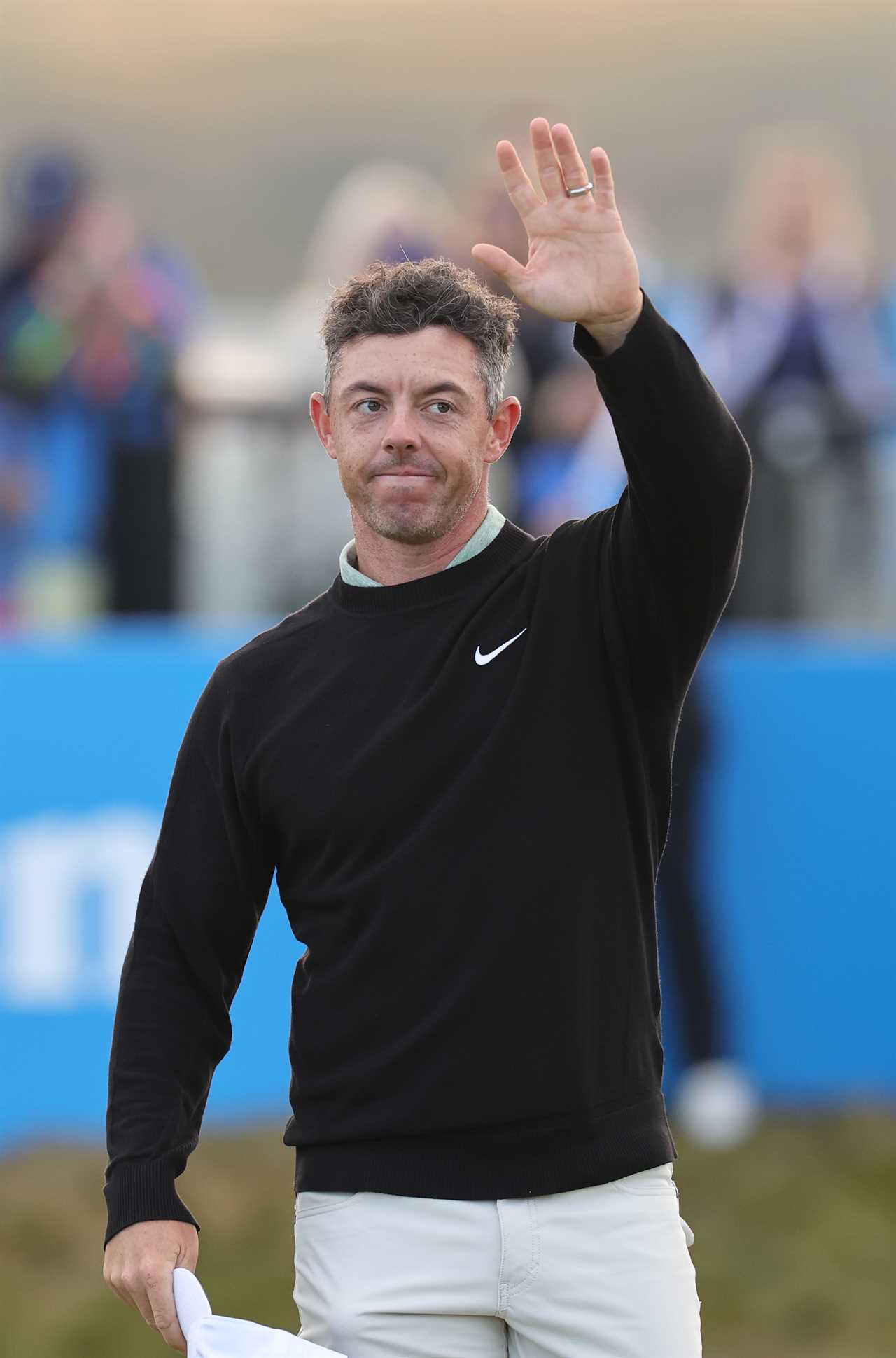 a man wearing a black nike sweater waves his hand