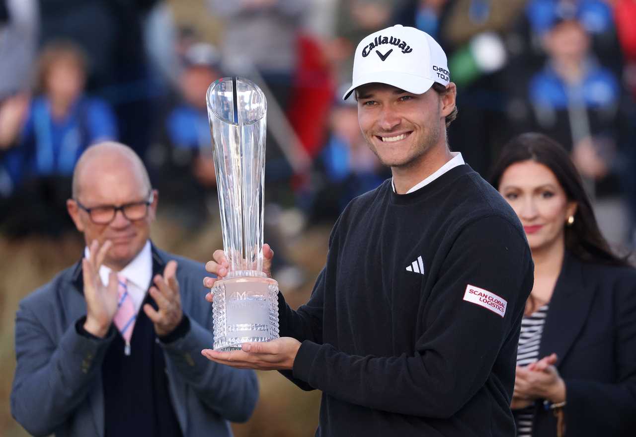 a man wearing a callaway hat is holding a trophy