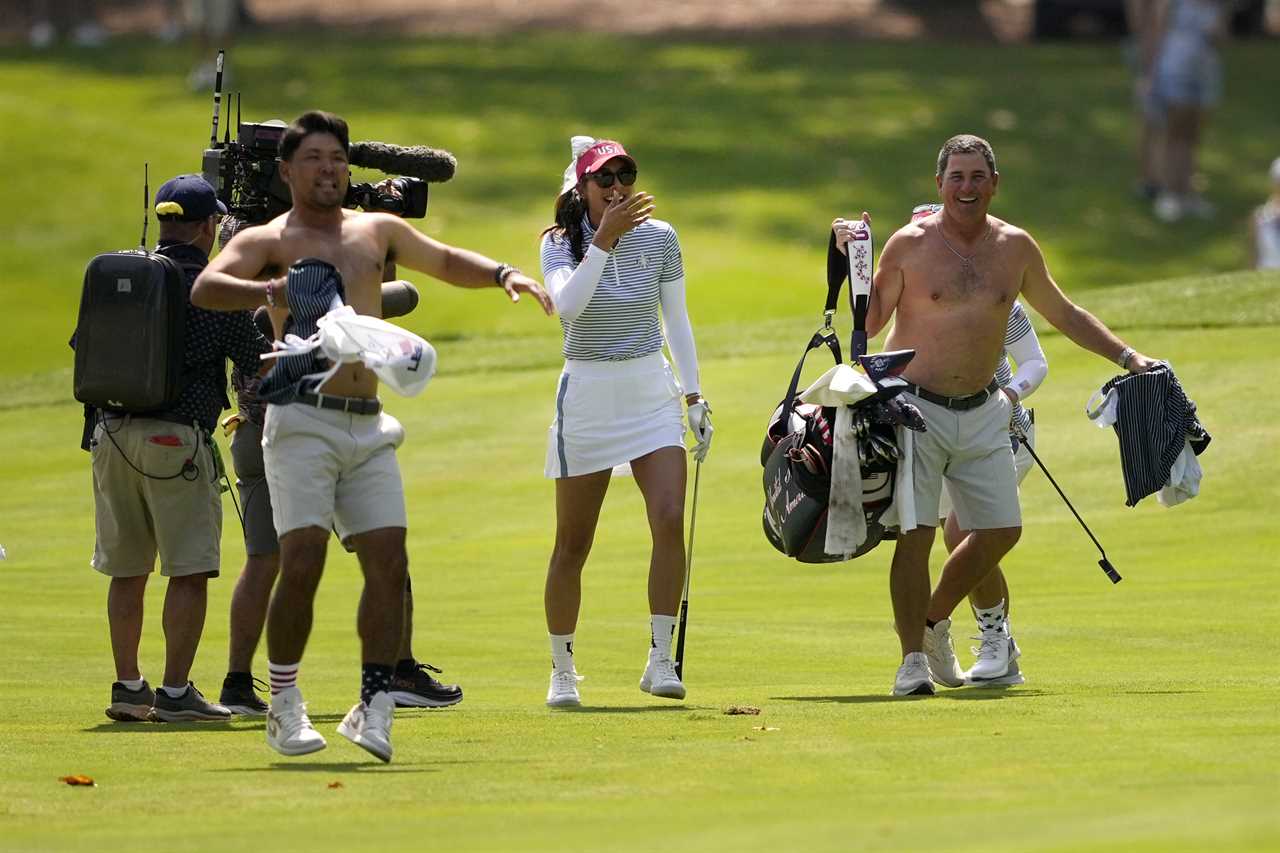 a group of people walking on a golf course with a cameraman behind them