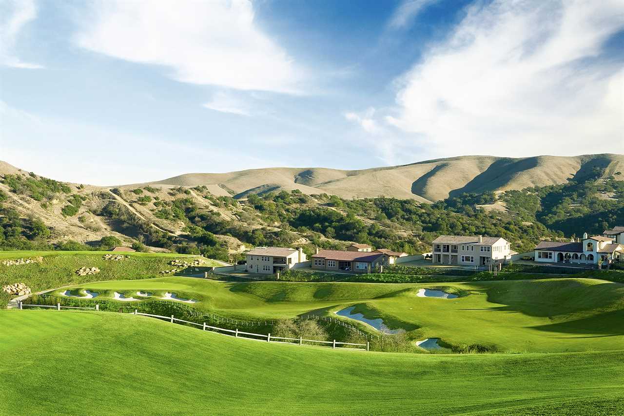 a golf course with houses in the background and mountains in the background