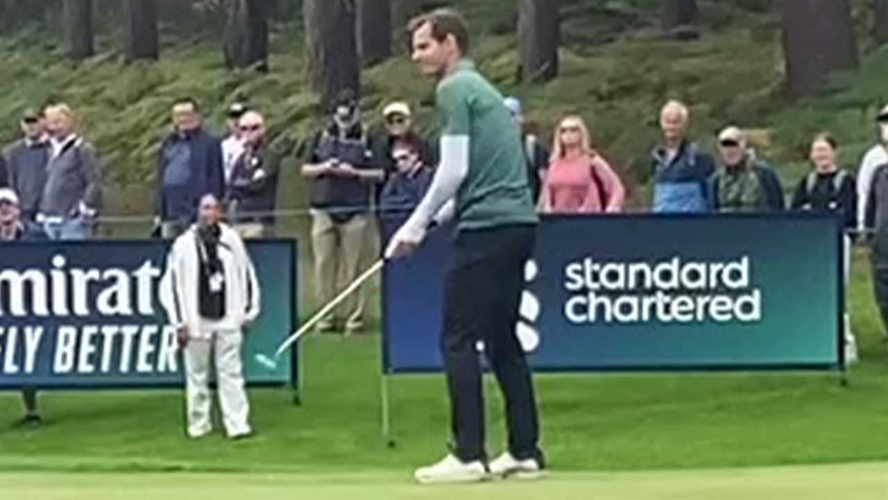 a man is standing on a golf course holding a golf club .