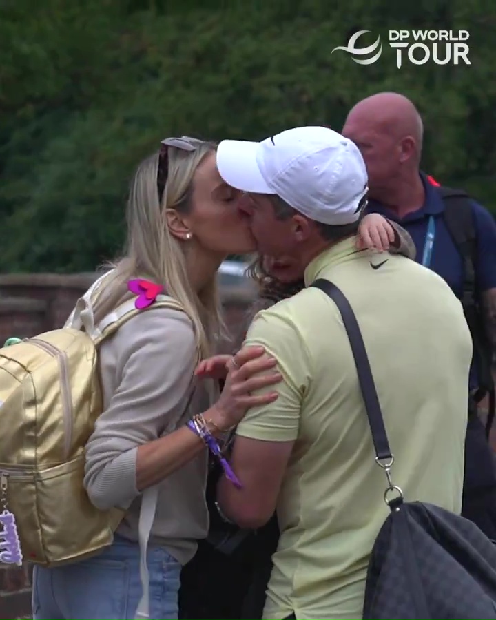 a man and woman kissing in front of a sign that says dp world tour