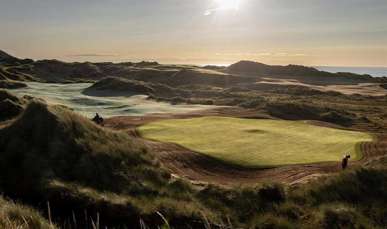 a golf course with the sun shining through the clouds