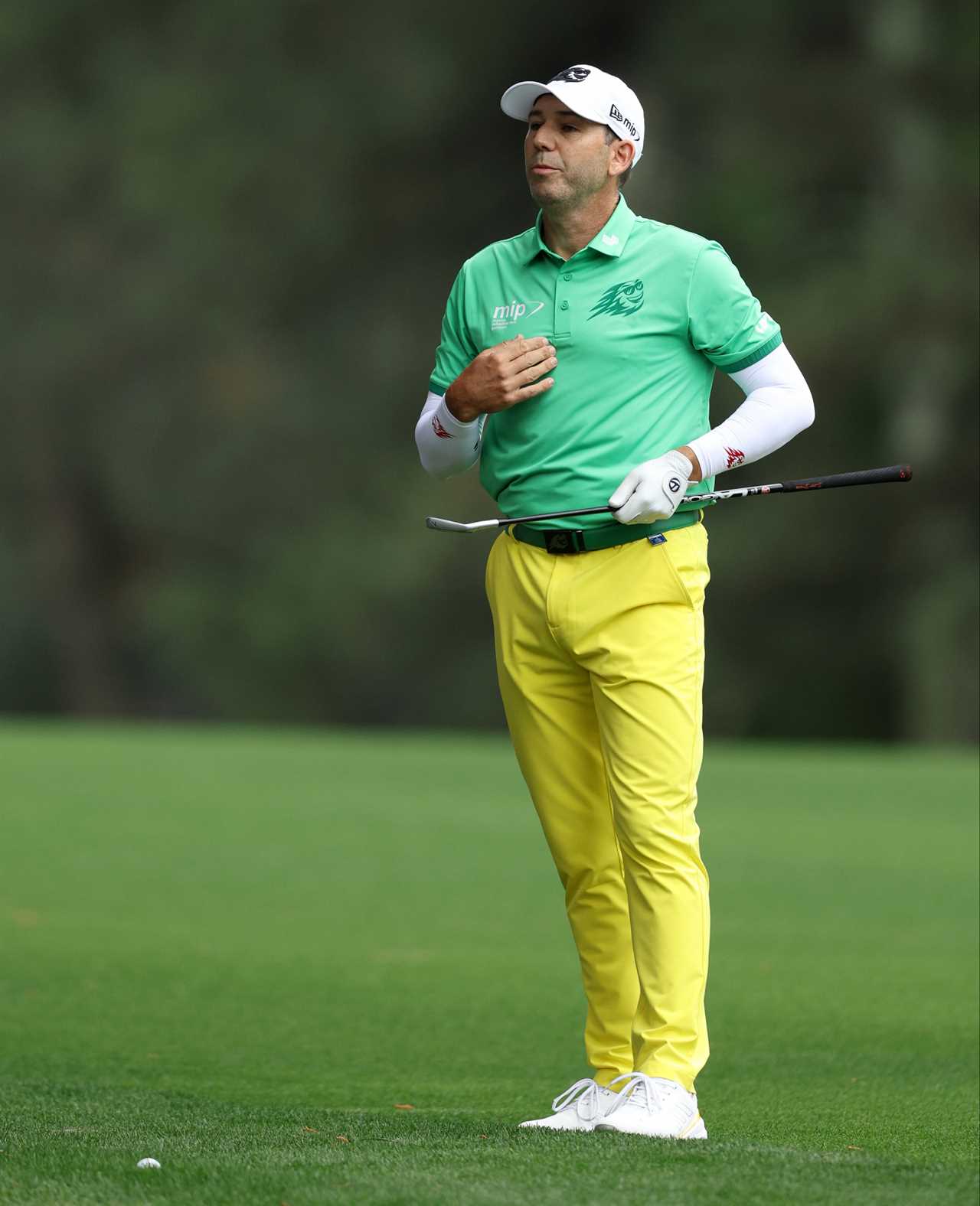 a man in a mip shirt holds a golf club