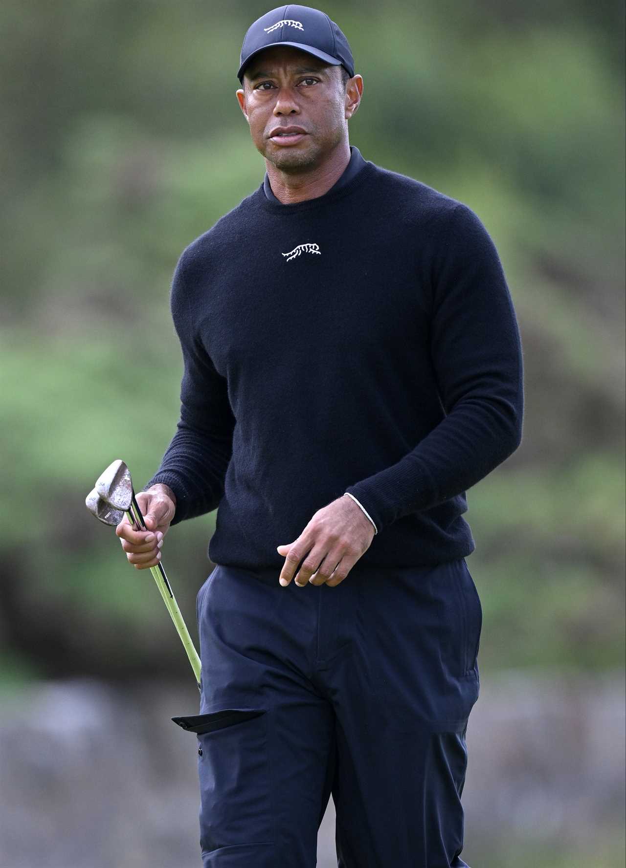 a man wearing a hat that says tiger woods is holding a golf club