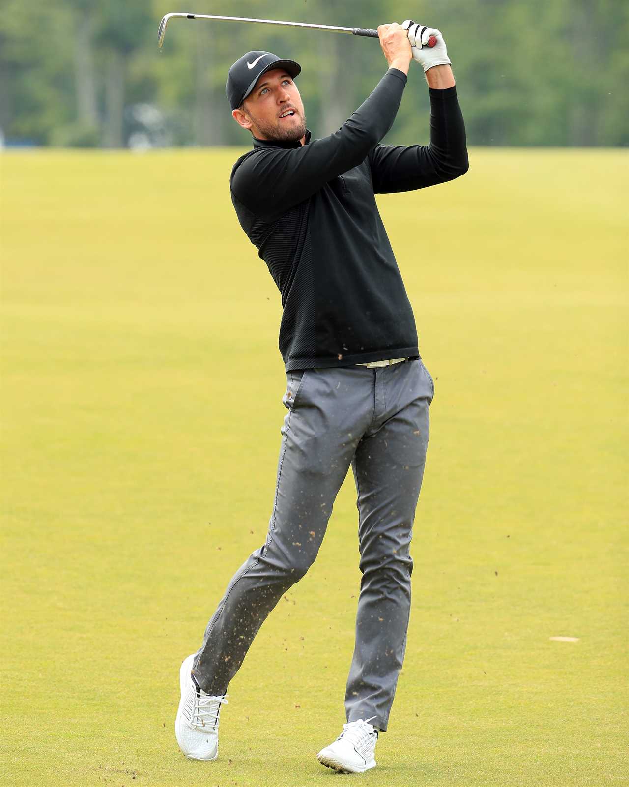 a man wearing a nike hat is swinging a golf club