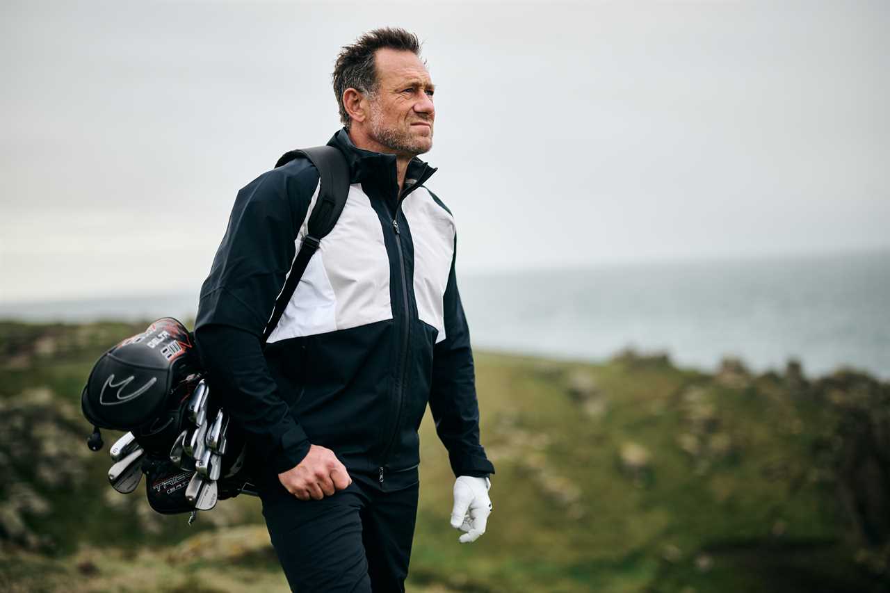 a man carrying a bag of golf clubs with the letter m on it