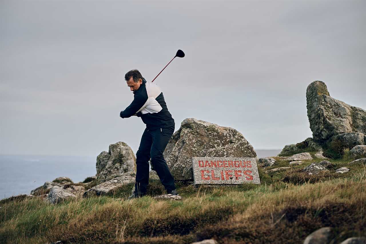 a man swings a golf club in front of a sign that says dangerous cliffs