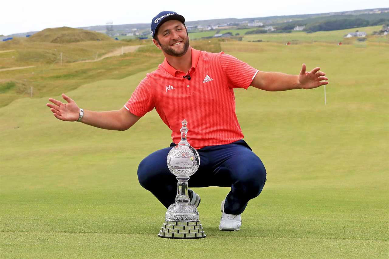 a man in a red adidas shirt kneeling next to a trophy