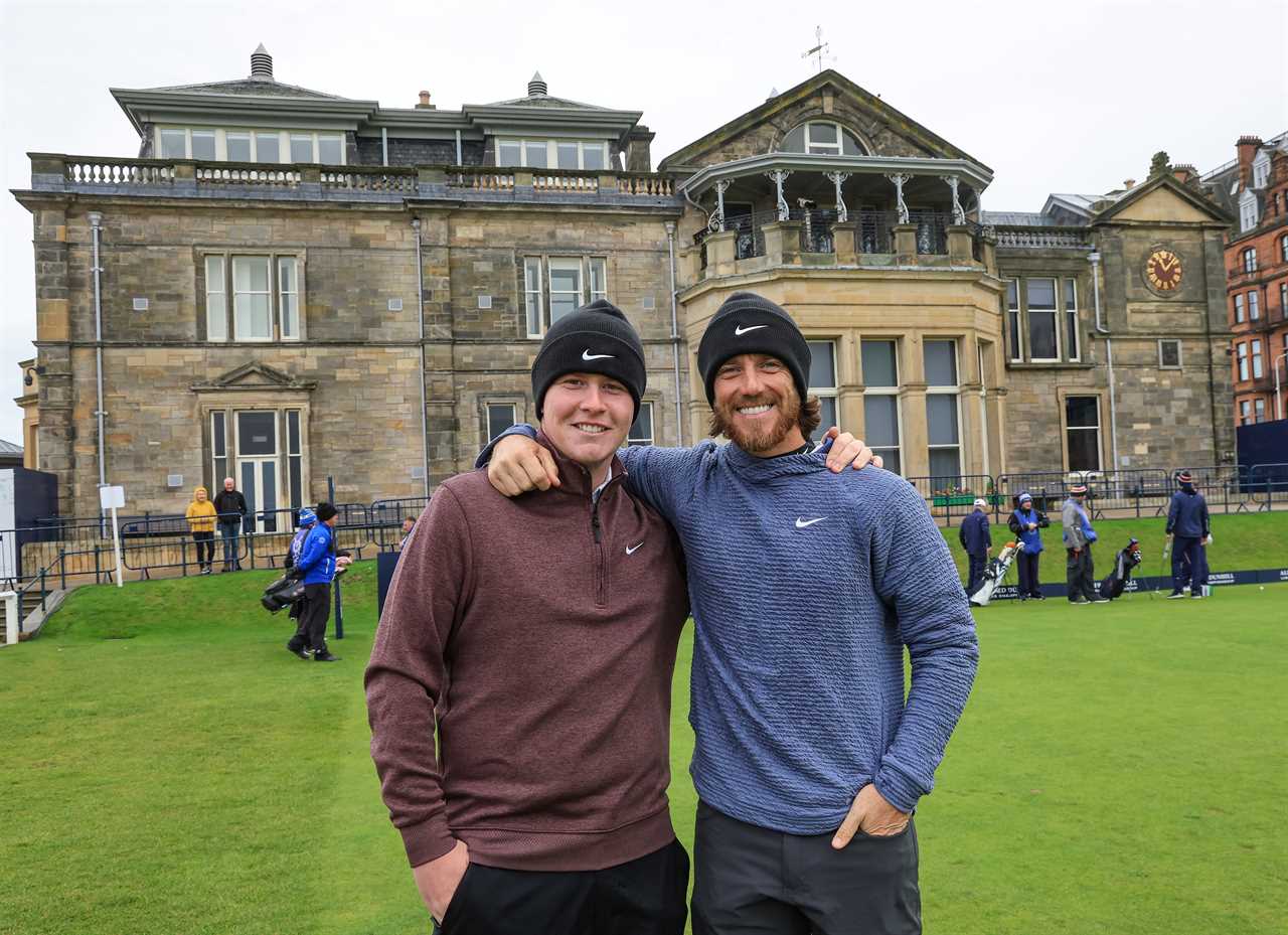 two men are posing for a picture in front of a large building