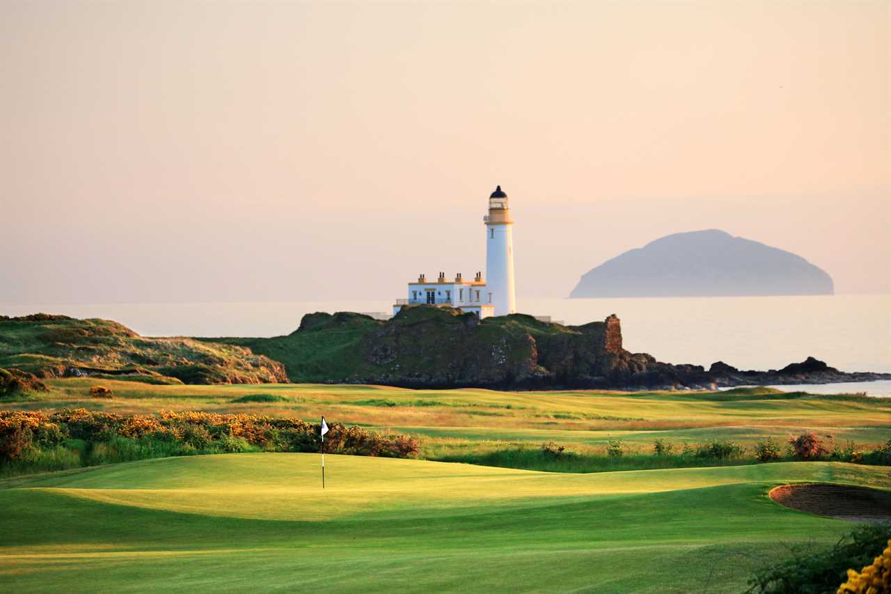 a golf course with a lighthouse in the background