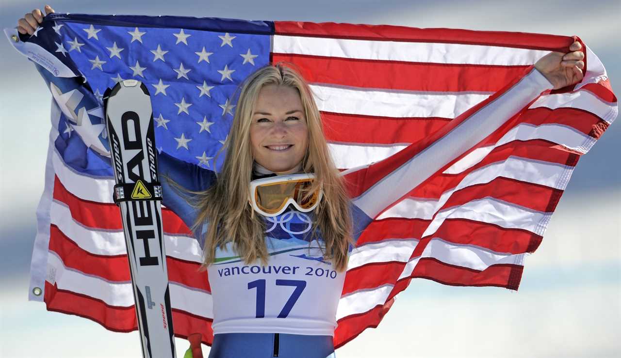 a woman holding an american flag and a pair of head skis