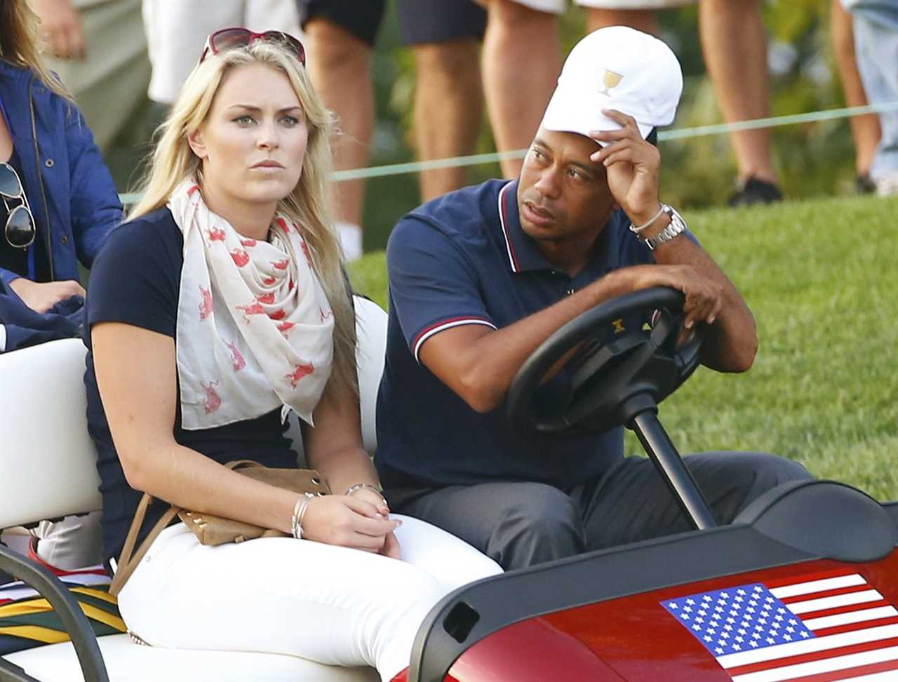 a man and a woman sit in a golf cart with an american flag on it