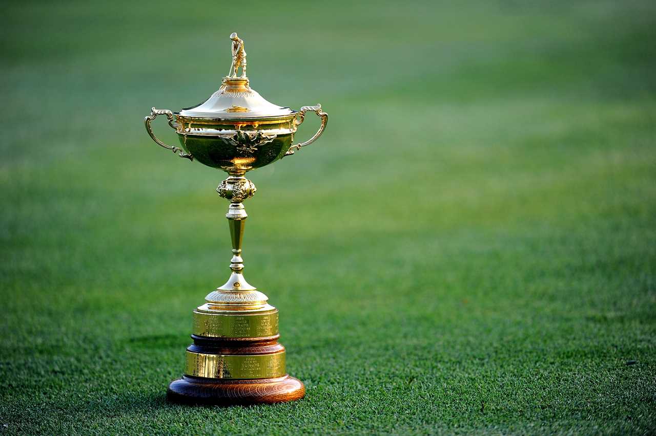 a gold trophy on a green field that says ' ryder cup ' on it