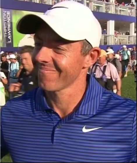 a man wearing a hat and a blue shirt is smiling on a golf course .