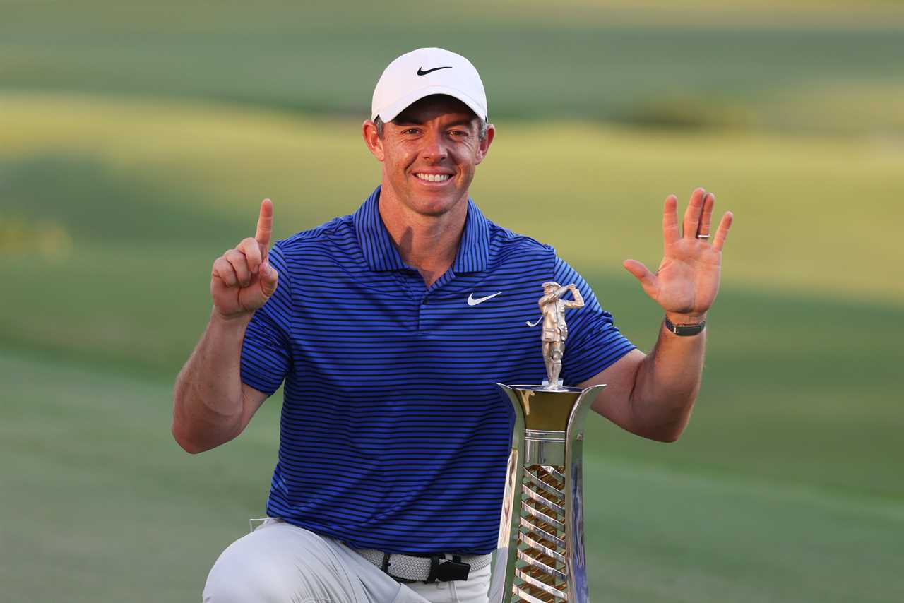 a man in a blue and white striped shirt is holding a trophy