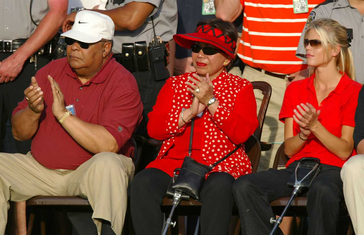 Tiger Woods' father, mother, and girlfriend applaud at a ceremony.