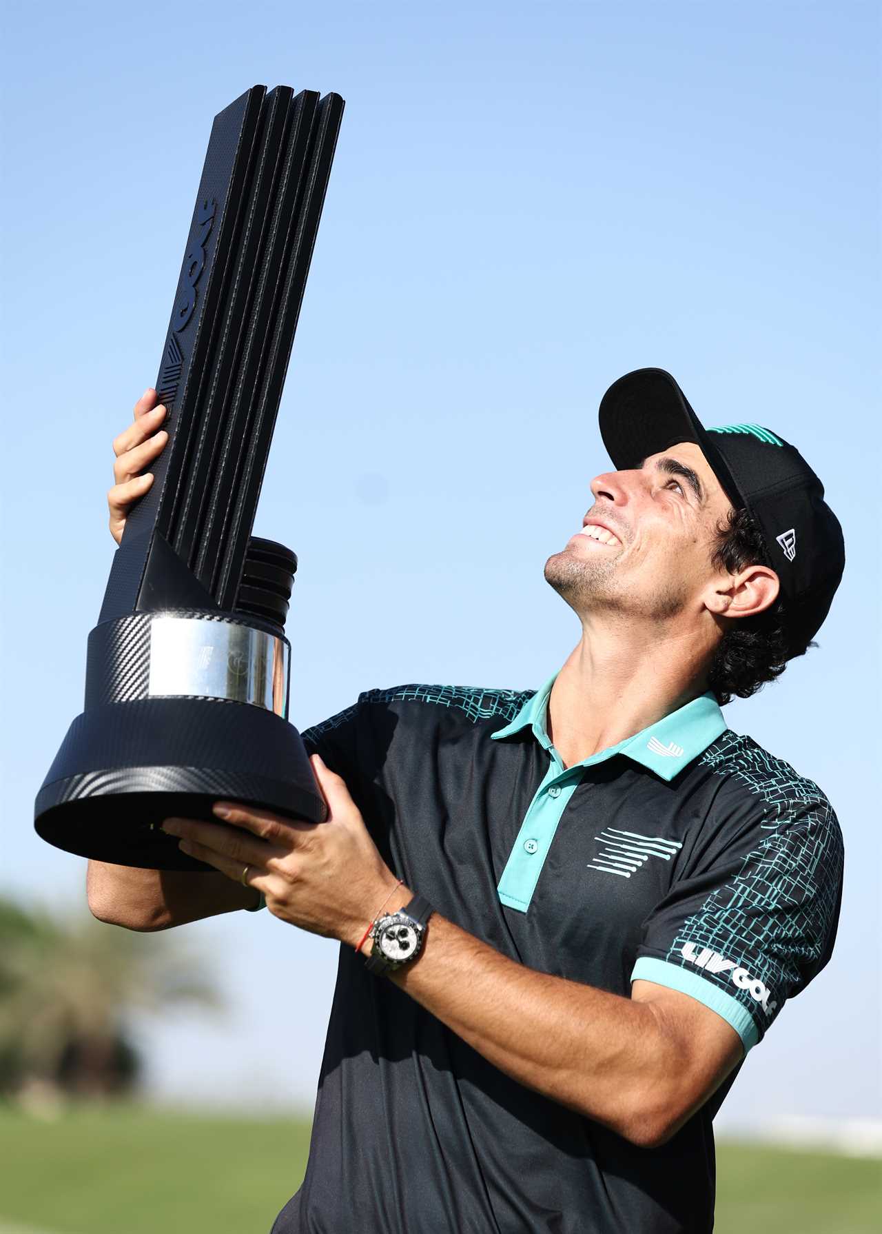 Joaquin Niemann holding a golf trophy.