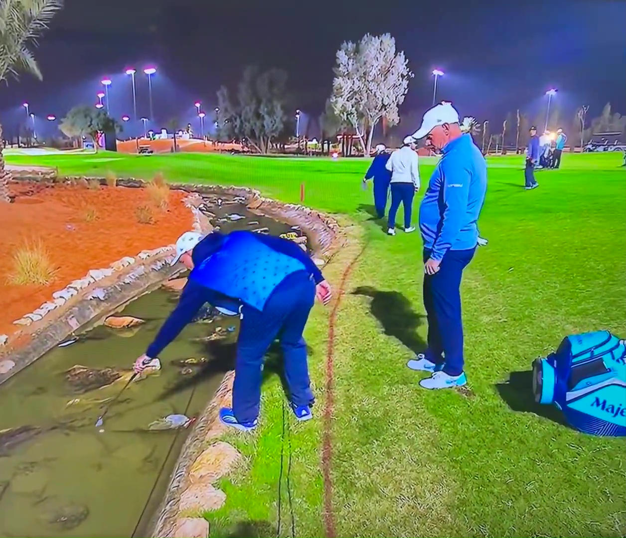 Lee Westwood retrieving his golf ball from a water hazard.