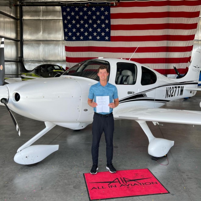 Man holding certificate in front of small airplane.