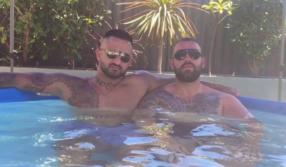 Two men with tattoos relaxing in a pool.