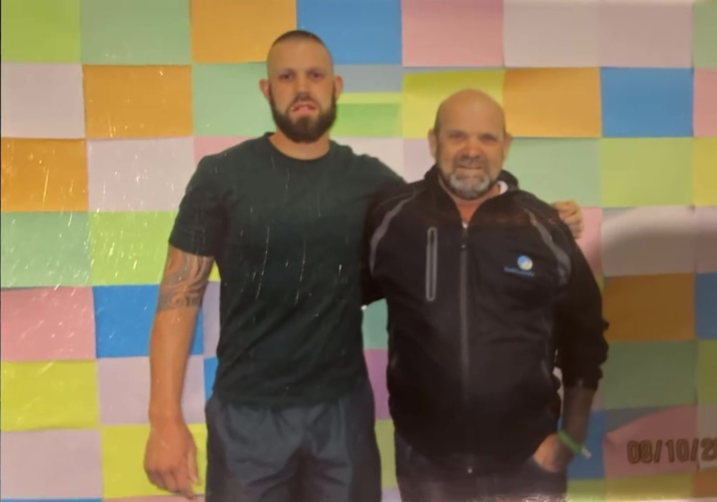 Two men posing for a photo in front of a colorful wall.