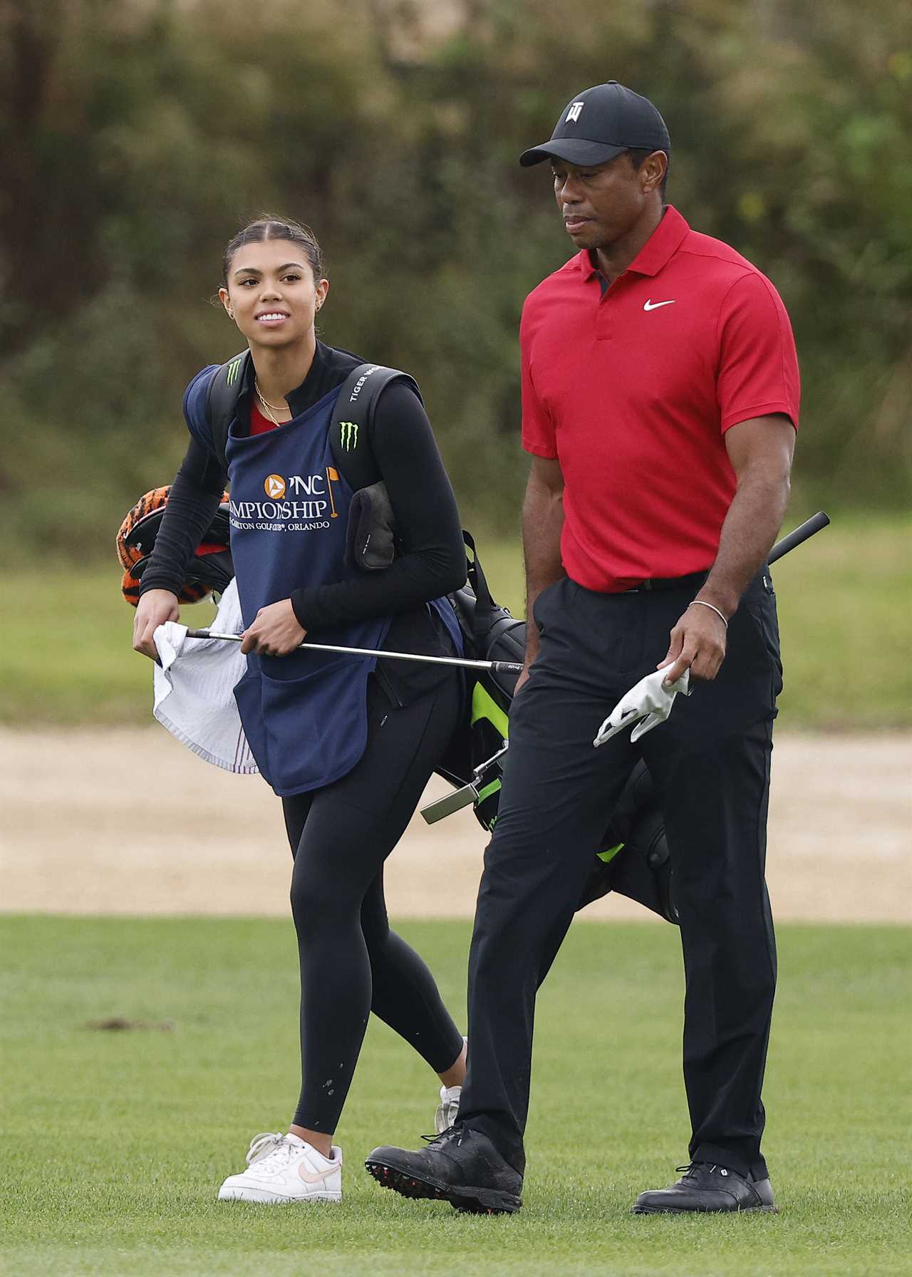 Tiger Woods and his daughter walking on a golf course.