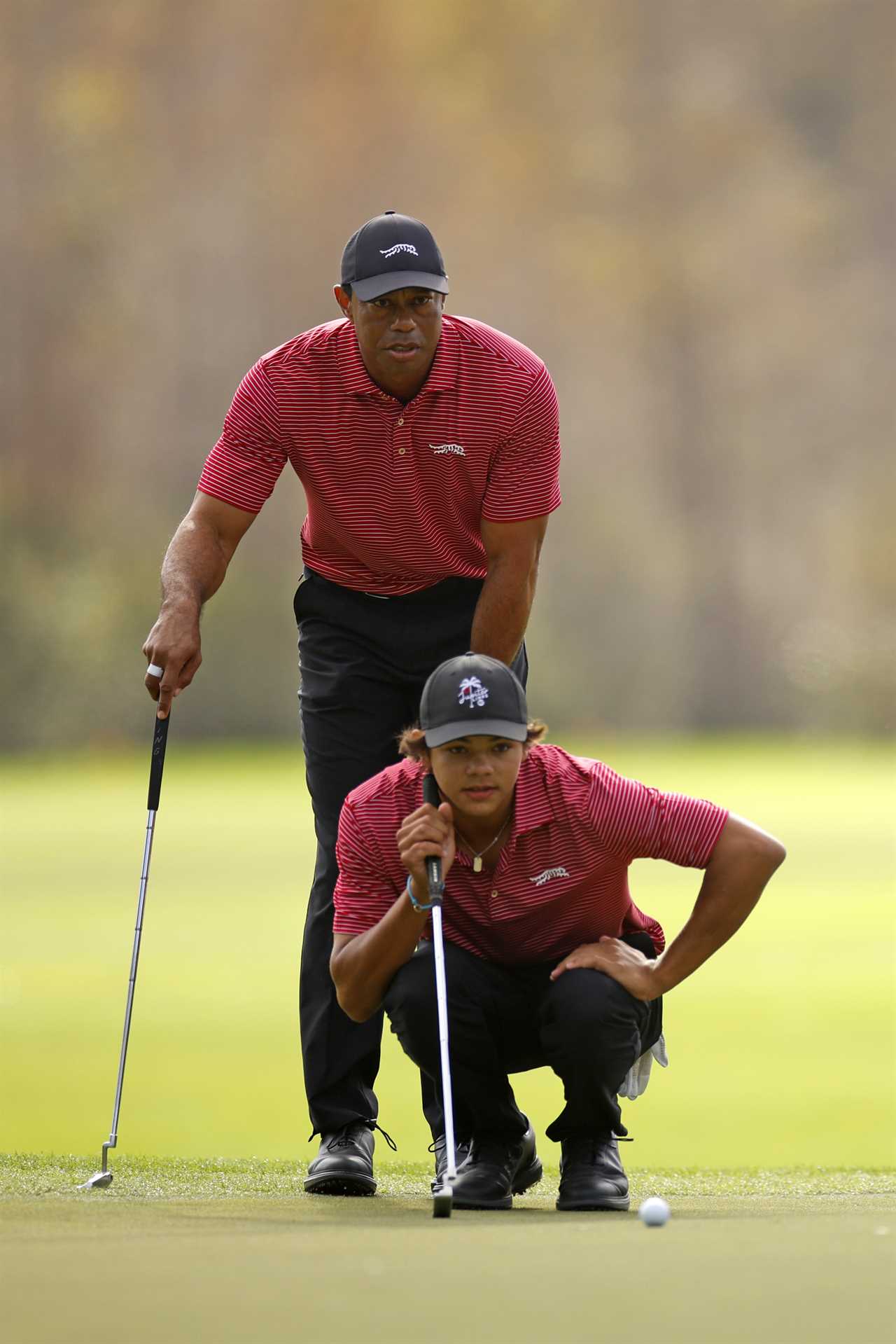 Tiger Woods watches his son Charlie Woods putt on the green.