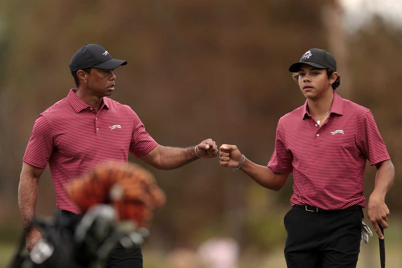 Tiger Woods and his son Charlie Woods fist-bumping on a golf course.