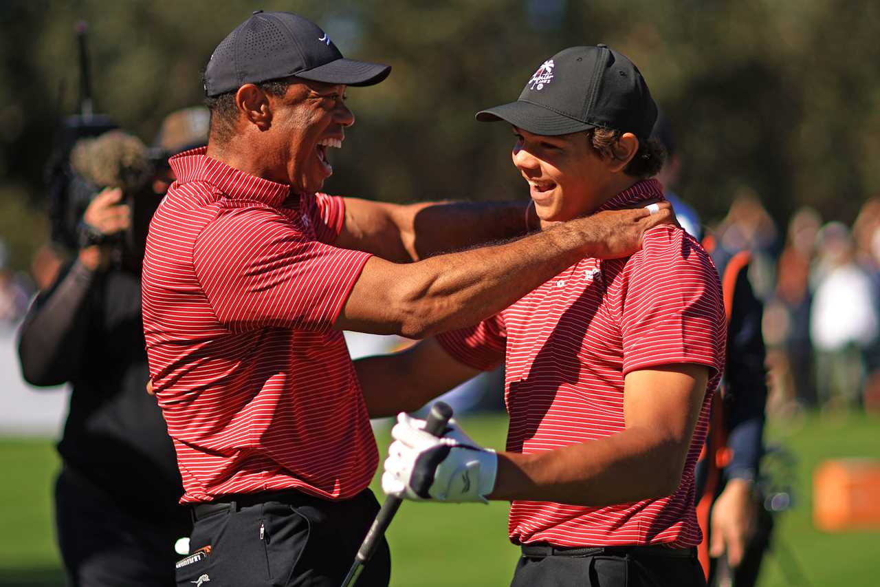 Tiger Woods and his son Charlie Woods embrace after a successful golf shot.