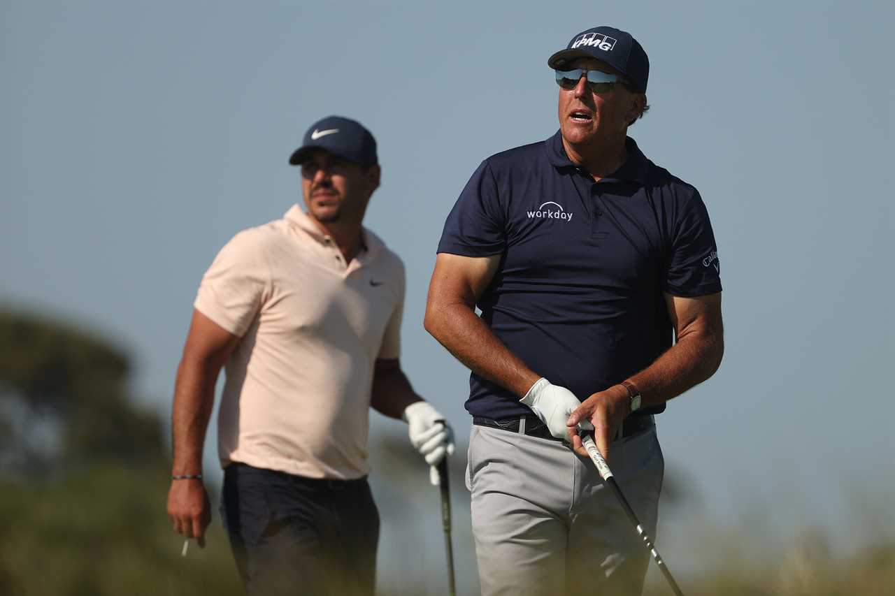 Phil Mickelson and Brooks Koepka watching a golf shot.