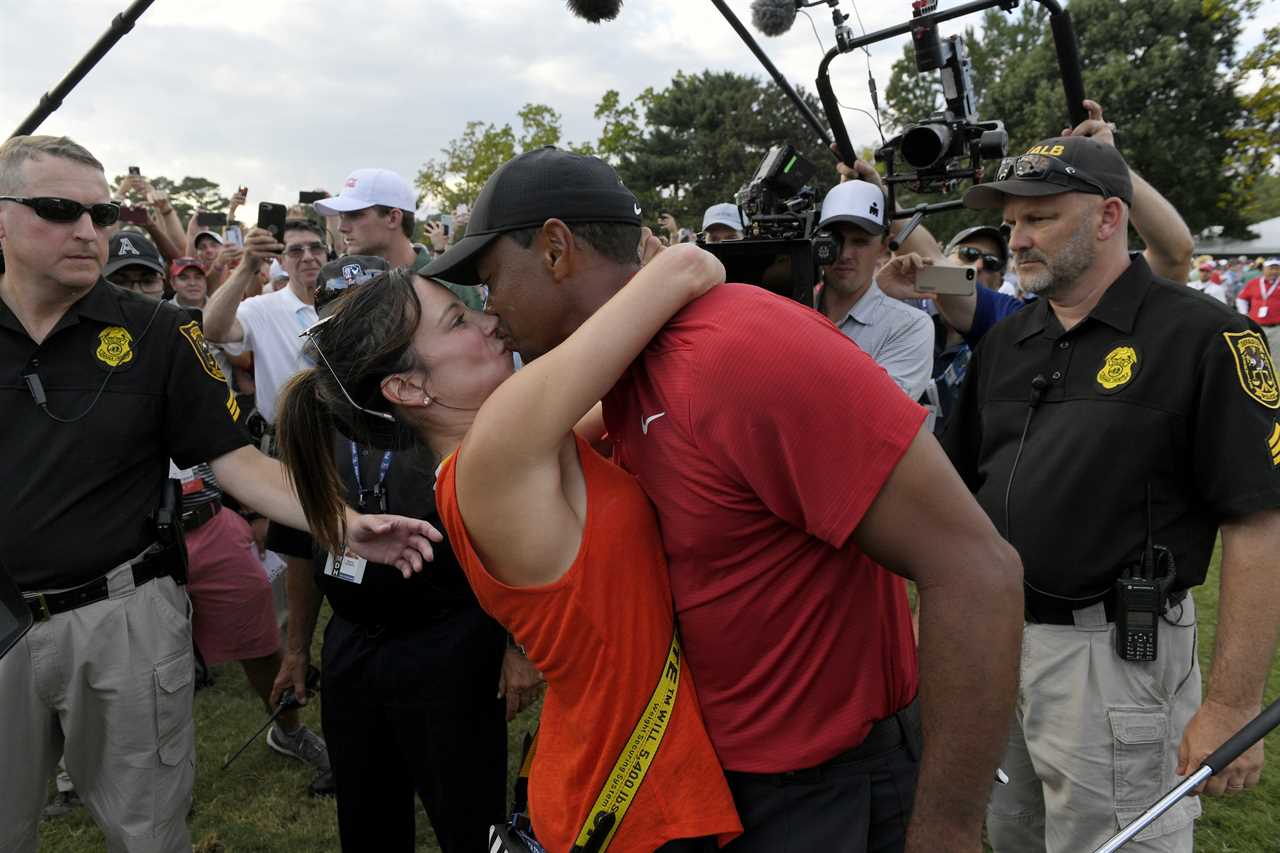 Tiger Woods and his girlfriend kissing after a golf tournament.