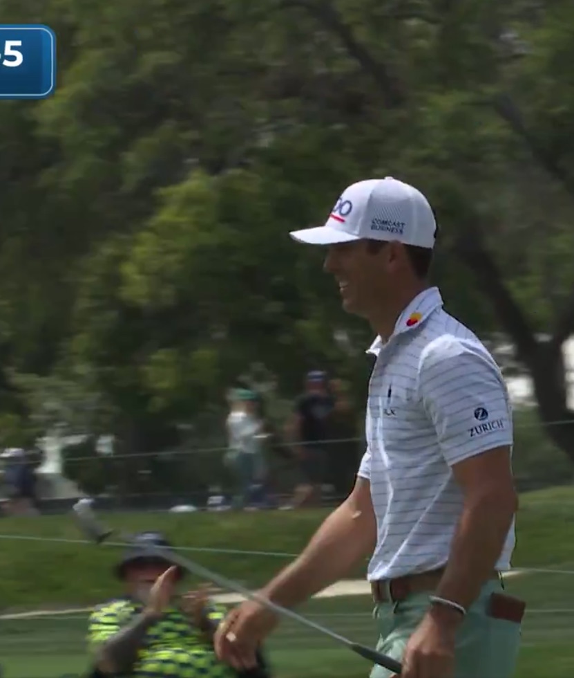 Golfer walking off the green with his putter.