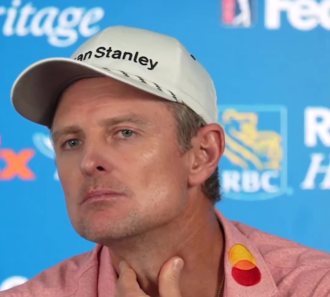 Close-up of a man in a pink shirt and white hat at a press conference, with text overlay asking, "Why do you have energy?"