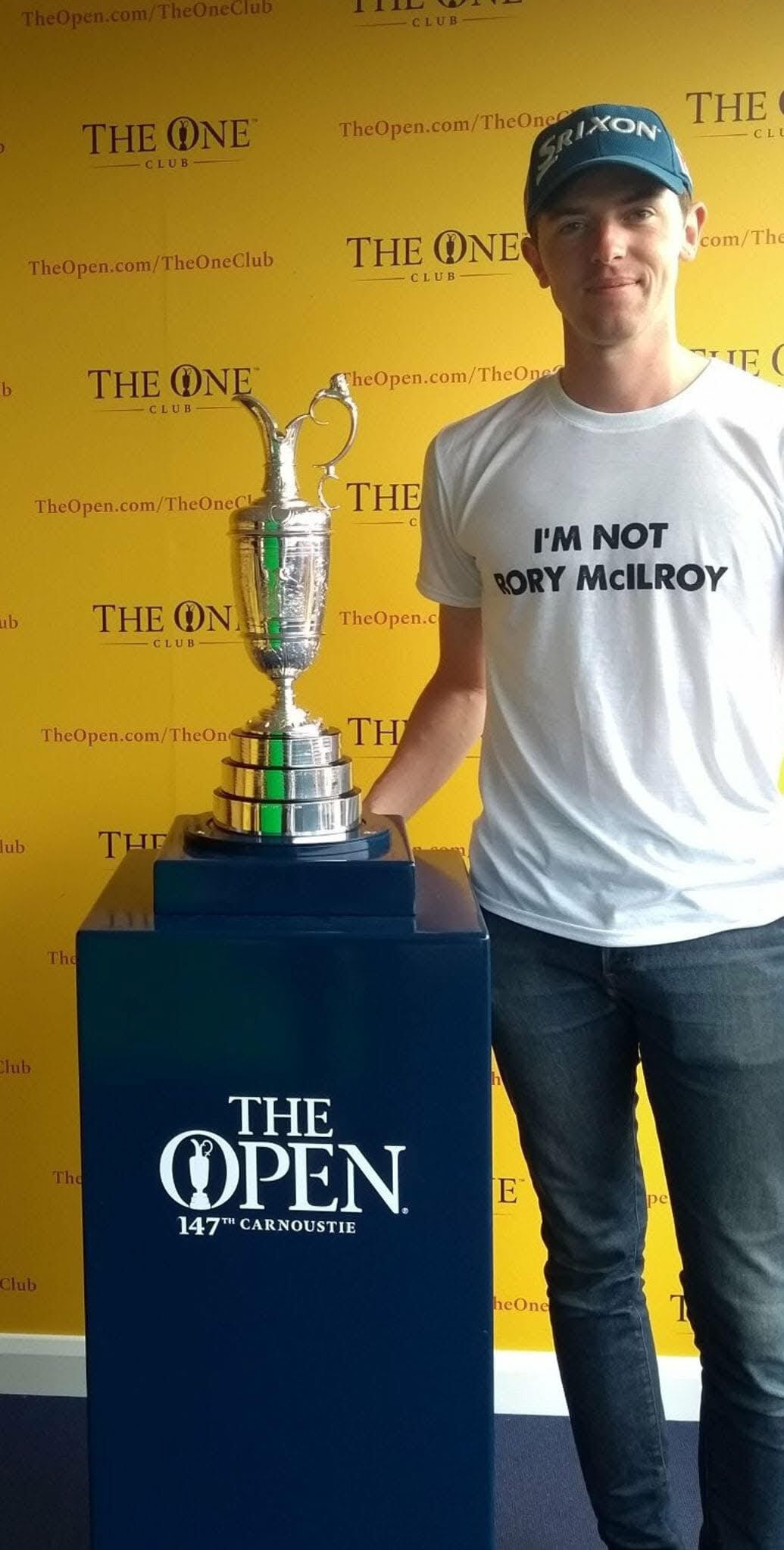 Man in "I'm not Rory McIlroy" t-shirt standing next to The Open Championship trophy.