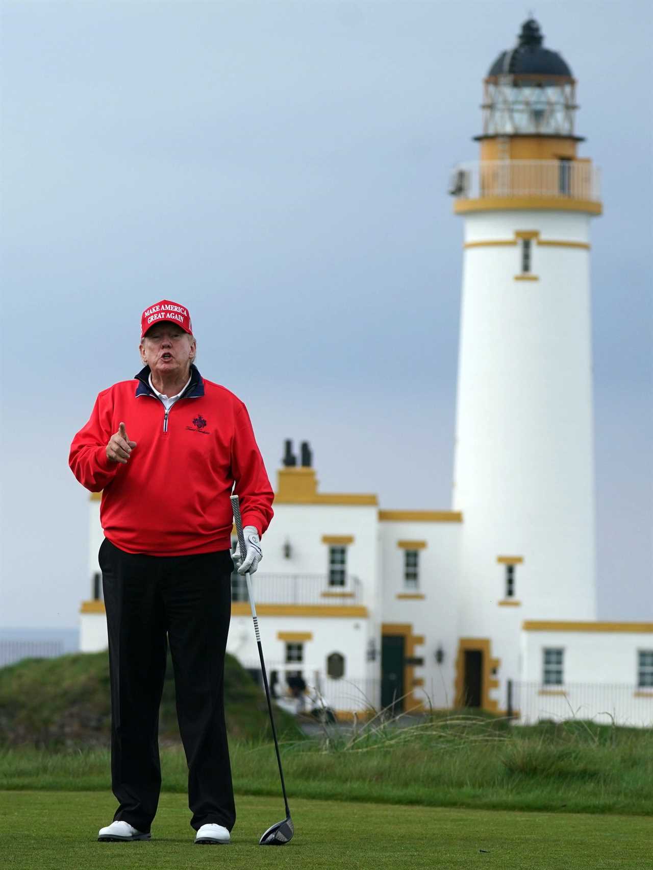 Donald Trump playing golf with a lighthouse in the background.