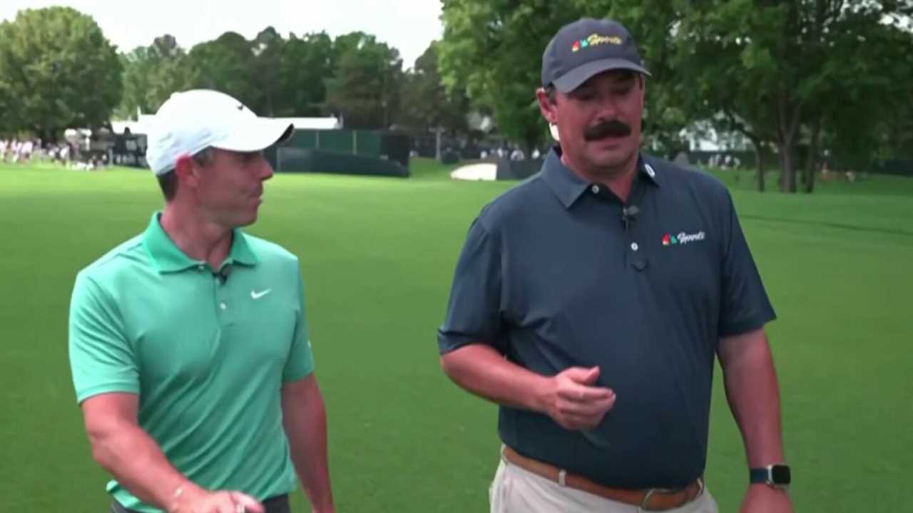 Two men walking and talking on a golf course.