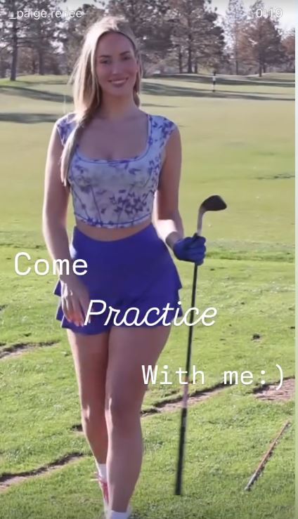 Paige Spiranac on a golf course, holding a golf club.