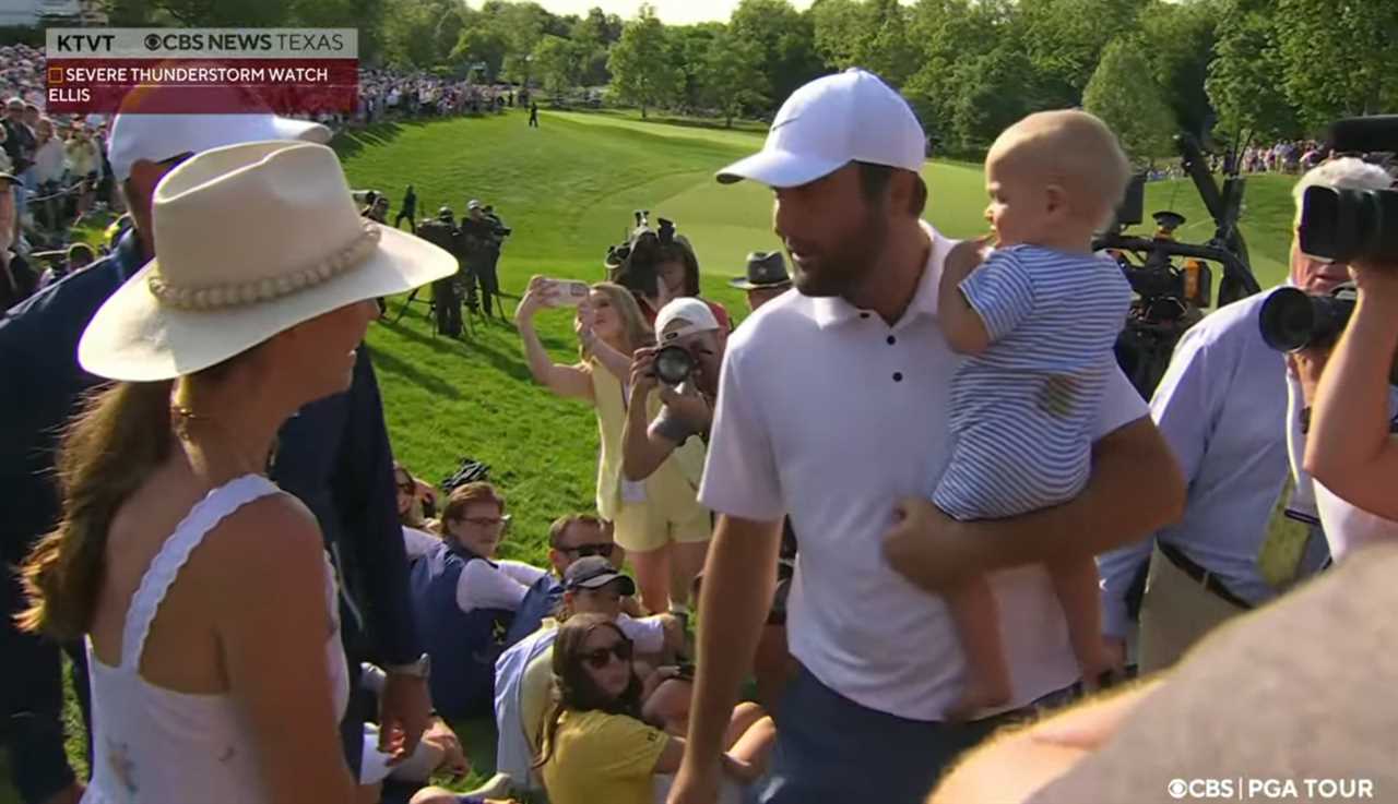 Scottie Scheffler holding his baby while surrounded by people on a golf course.