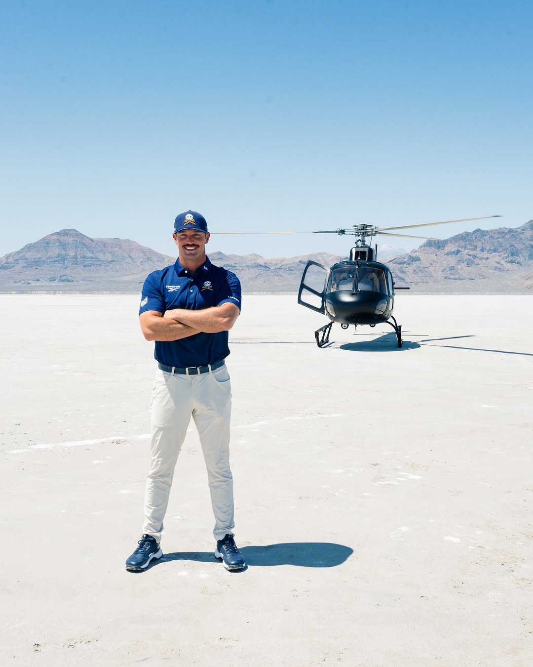 Bryson DeChambeau standing in front of a helicopter.