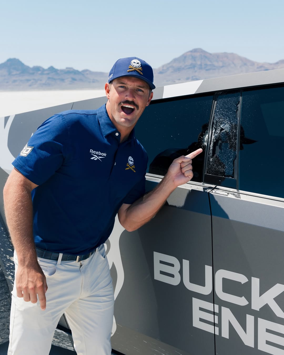 Bryson DeChambeau points to a damaged car window.