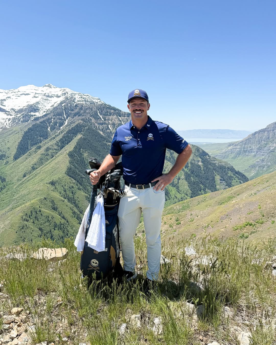 Bryson DeChambeau pointing at a damaged car window.