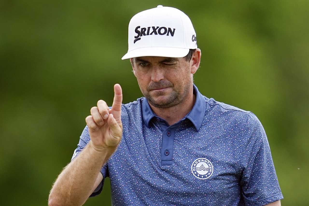 Keegan Bradley, wearing a Srixon hat, points with one finger.